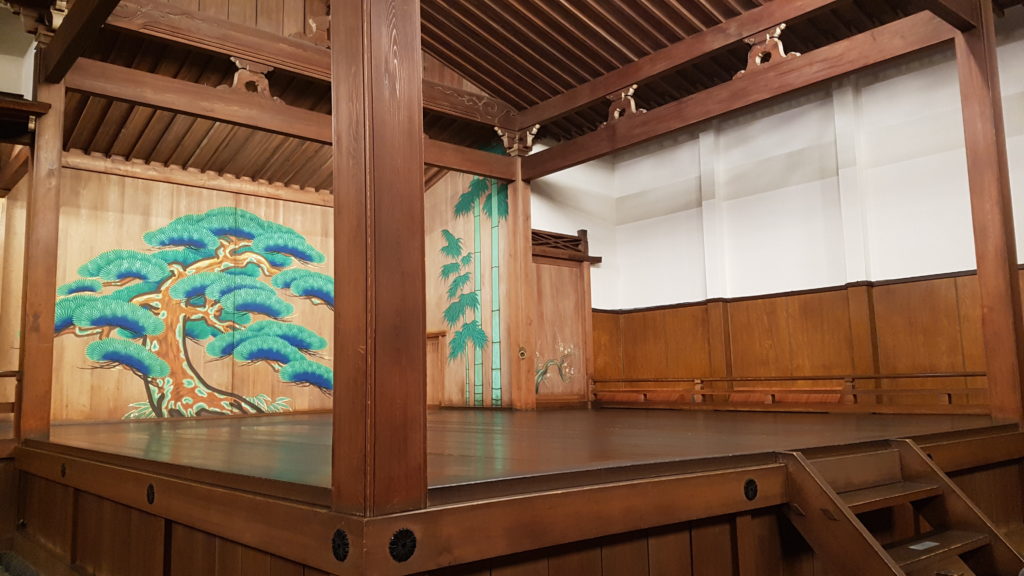 A small set of wooden stairs descend from the front of the noh stage