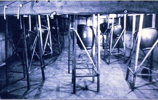 Clay jars are mounted in wooden braces under a wooden noh stage