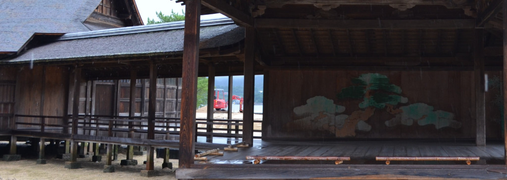 The bridgeway and stage of a weathered, wooden noh stage at Itsukushima Shrine.