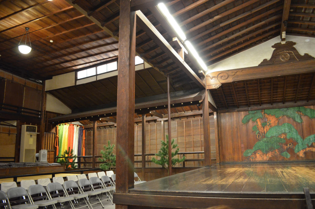 Side seating of a nogaku stage comprised of tatami terraces and metal folding chairs.