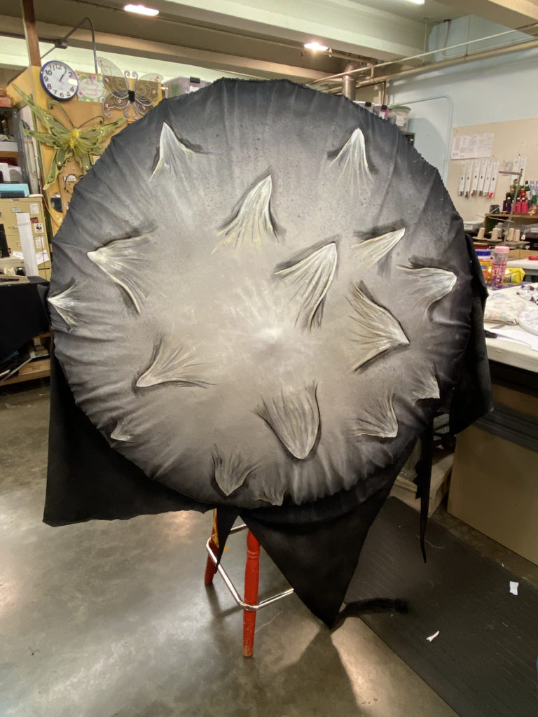 A birds eye view of an umbrella painted to look like an inky cap mushroom.